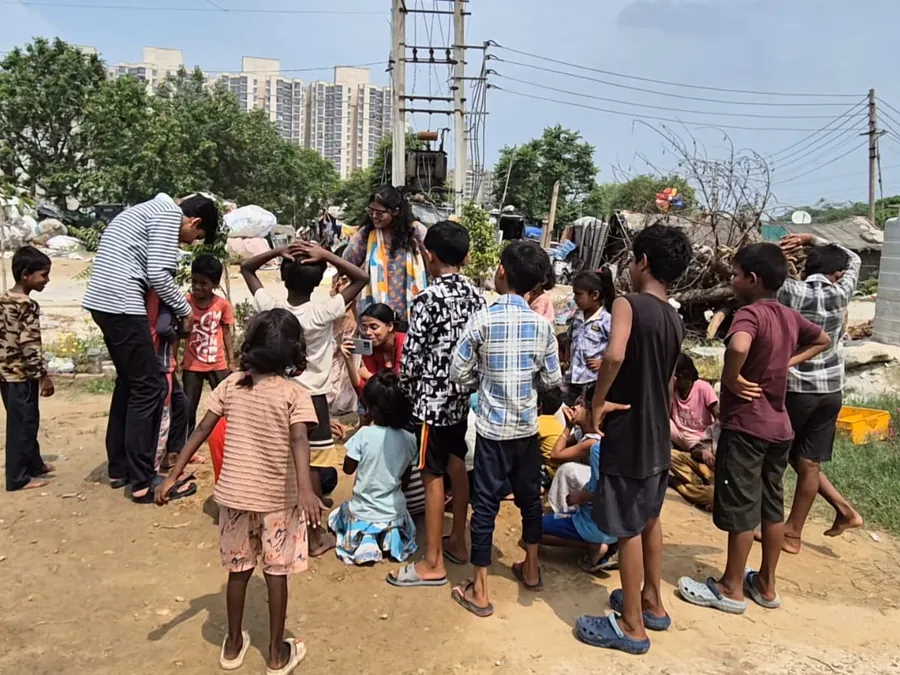 Children outdoors, with the city's high-rises rising behind the settlement.